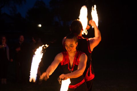 Weltentor Feuershow – zwei Personen schwingen brennende Stäbe
