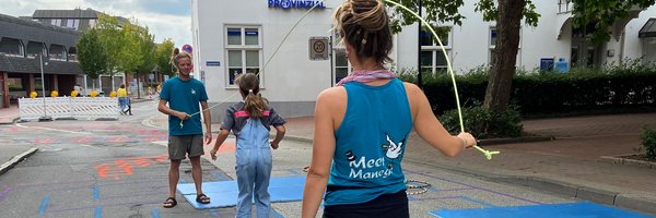 Drei Personen springen Springseil auf der bemalten Straße - Schwarzer Weg. 