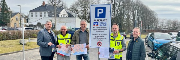 Zeitweise Freigabe der VR-Parkplätze: H. Schütze (Stadtmarketing), D. Jürgensen (FD Tiefbau), M. Möller (Vorstand VR-Bank Nord), T. Krüger (FD-Leiter Tiefbau) und R. Gottschalk (VR Bank Nord) vor einem Schild mit Öffnungszeiten