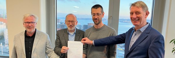 Bernward Völmicke, Stadt Schleswig, Bernd Hannemann, Diakonie Stiftung Schleswig-Holstein, Alexander Opitz, Stadt Schleswig, Kay-Gunnar Rohwer, Diakonie Stiftung Schleswig-Holstein halten einen unterschriebenen Kaufvertrag in der Hand